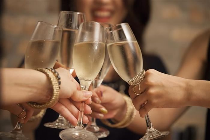 Group of elegantly dressed guests making a toast with champagne flutes at The Kitchens