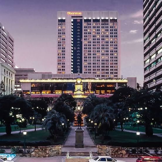 A large hotel of Sofitel Brisbane Central stands prominently with a clock tower rising in the background