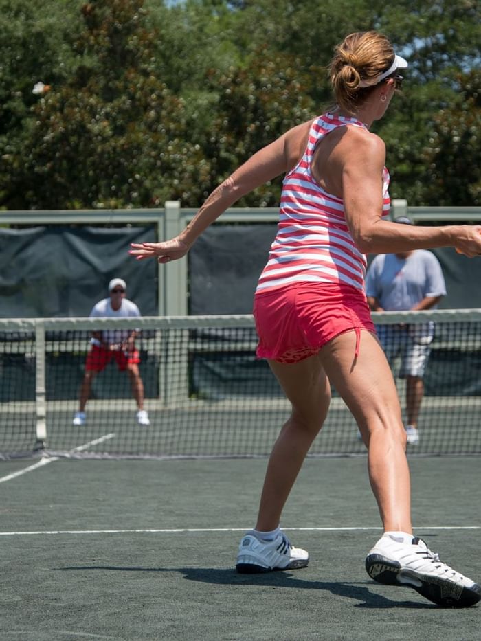 A girl playing tennis on a court near WaterColor Inn