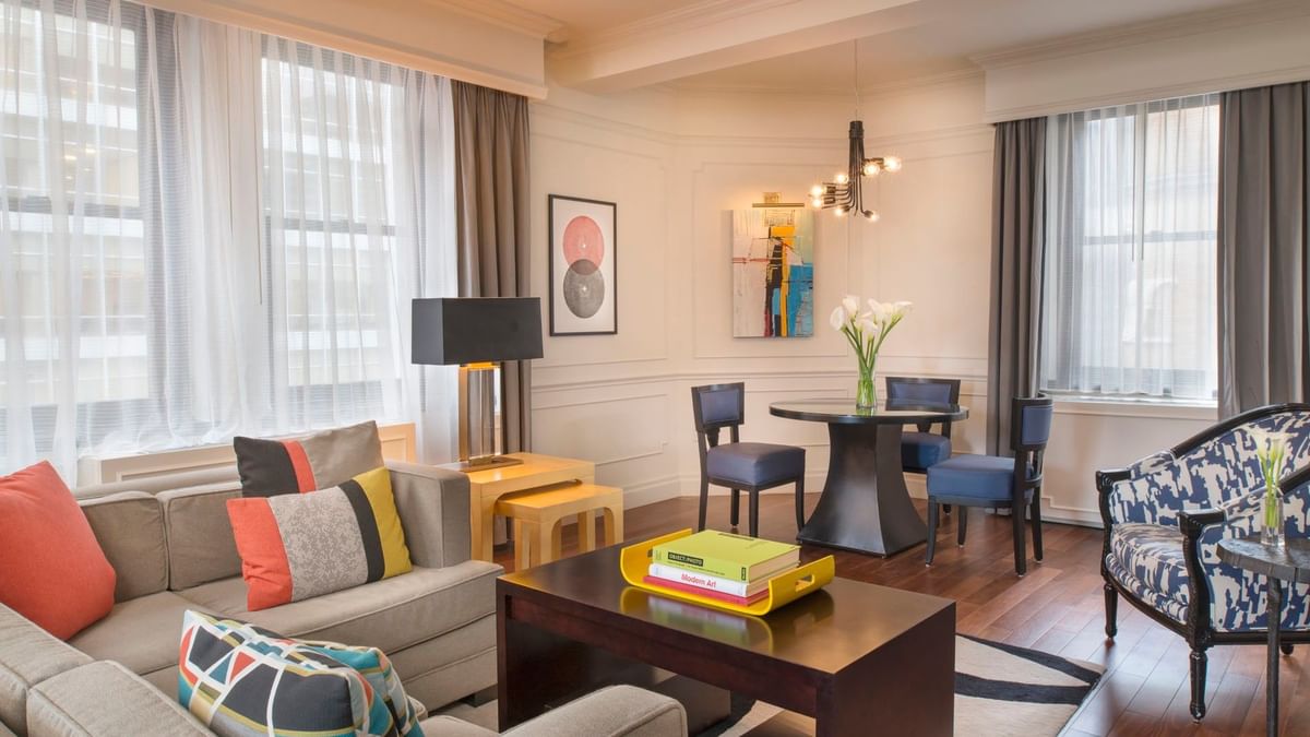 Colorful pillows with abstract art, and a dark wood table with small dining area in Modern Art Suite at Warwick New York