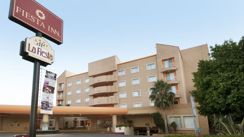 Modern seating area with colorful chairs and a large circular mirror at Fiesta Americana Travelty