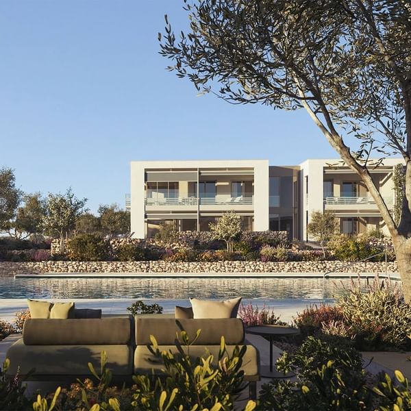 A modern building with a pool and lounge area, surrounded by greenery and trees.