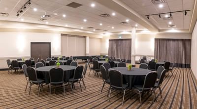 Black tablecloths on round tables under recessed lights at Rodd Miramichi River, a top choice for Miramichi events