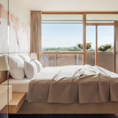 Geräumiges Schlafzimmer mit großem Bett, Balkon und moderner Einrichtung.