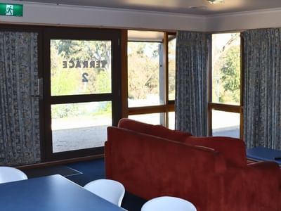 Terraces lounge area with red couch, blue tables, and curtains at La Trobe University.