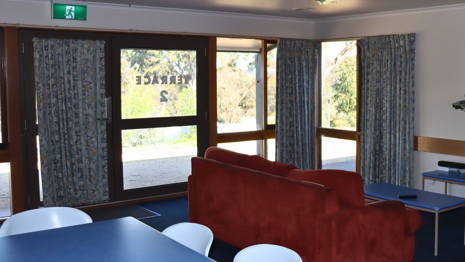 Terraces lounge area with red couch, blue tables, and curtains at La Trobe University.