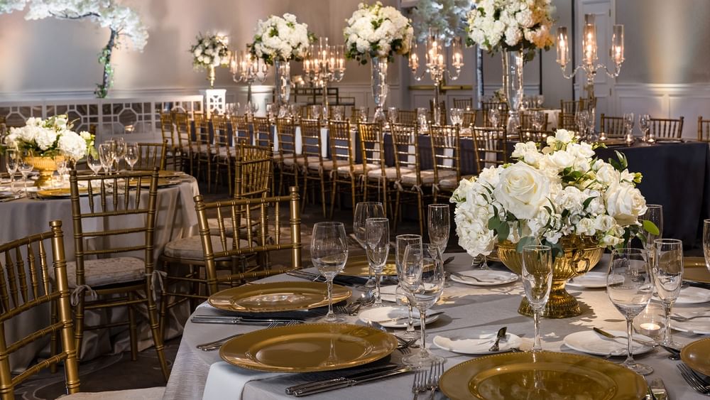 Elegantly set dining tables with floral centerpieces and gold accents in Turtle Creek Ballroom B at Warwick Melrose Dallas.