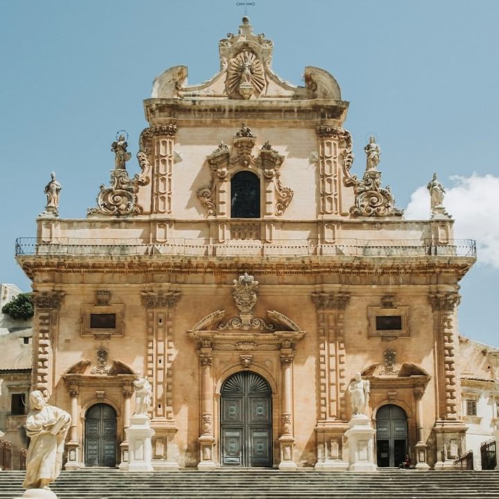 Barocke Fassade einer historischen Kirche mit Statuen und Treppen im Vordergrund.