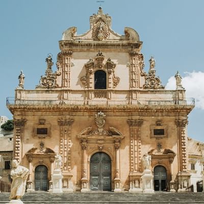 Barocke Fassade einer historischen Kirche mit Statuen und Treppen im Vordergrund.