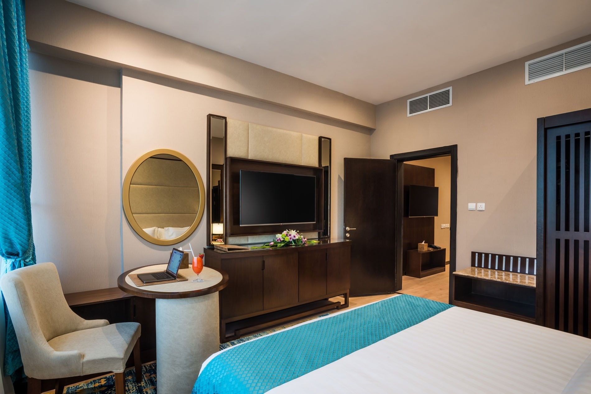 TV facing the bed with a work desk near the open door in the Executive suite at Naviti By Warwick Dammam