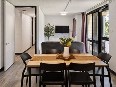 Modern dining area with wooden table, black chairs, and vase at UniLodge at Curtin University - Guild House.