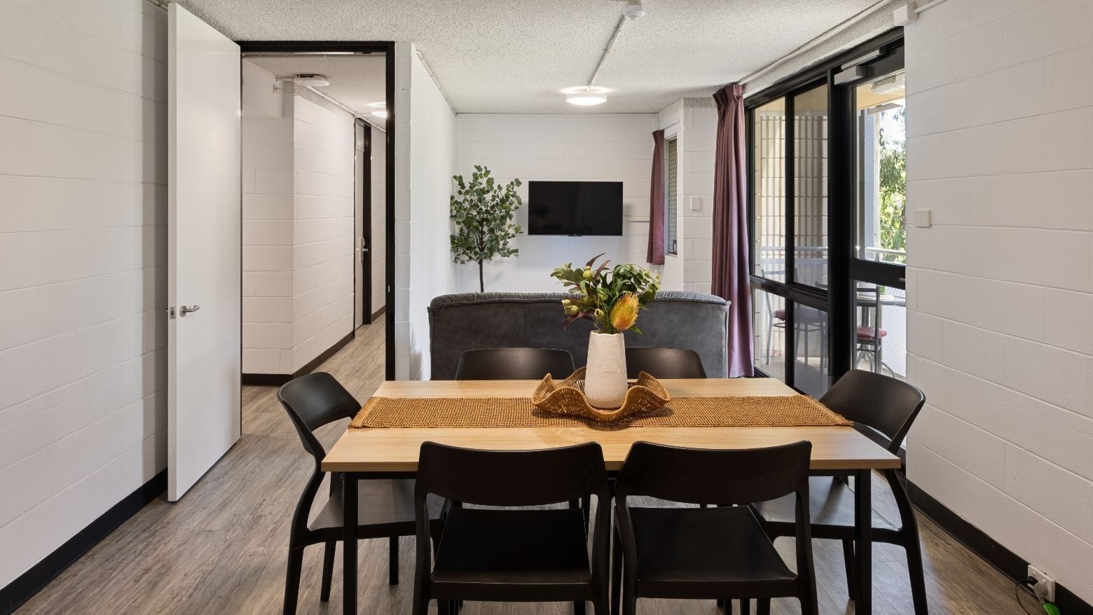Modern dining area with wooden table, black chairs, and vase at UniLodge at Curtin University - Guild House.