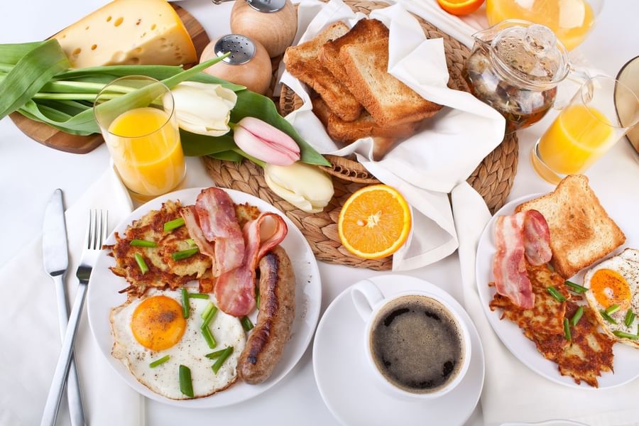 Full breakfast plates by black coffee under a basket of toast near tulips at Warwick San Francisco