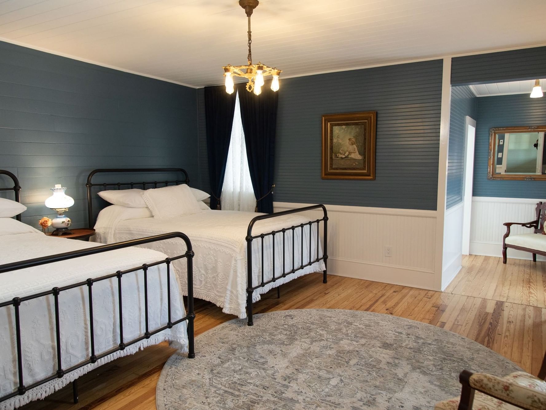 Beds beside a round rug and between blue walls with a framed painting in the Double Queen Room at Jarrett House