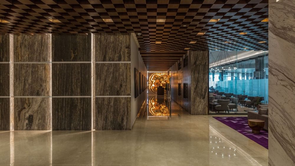 Corredor elegante con paredes de textura de piedra y piso de mármol pulido en Camino Real Mérida