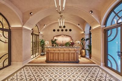 Elegant lobby featuring a wooden reception desk, arched ceilings, and decorative plants at Hotel Motto Vienna