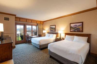 Double Queen Room at the Lake Placid Club Grandview, featuring two queen beds and a glass door leading to a private balcony