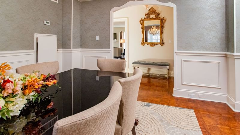 Presidential Suite dining area featuring a black table, and beige upholstered chairs at Warwick Melrose Dallas