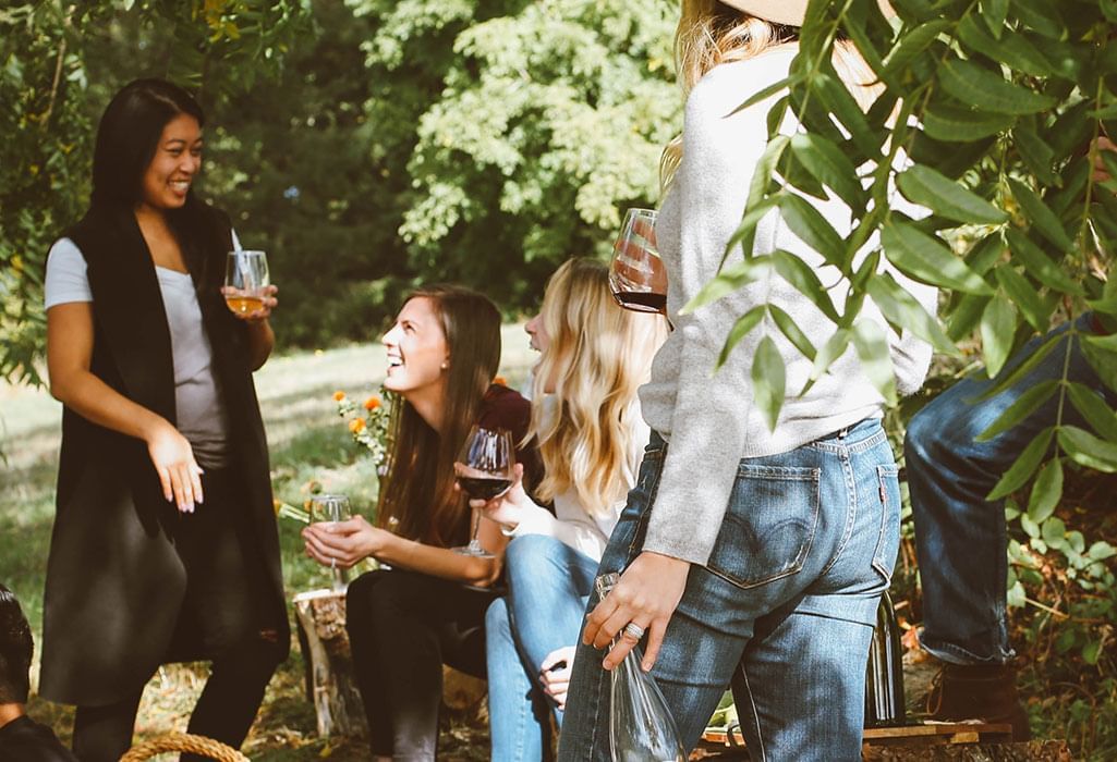 girlfriends drinking wine and laughing together outside