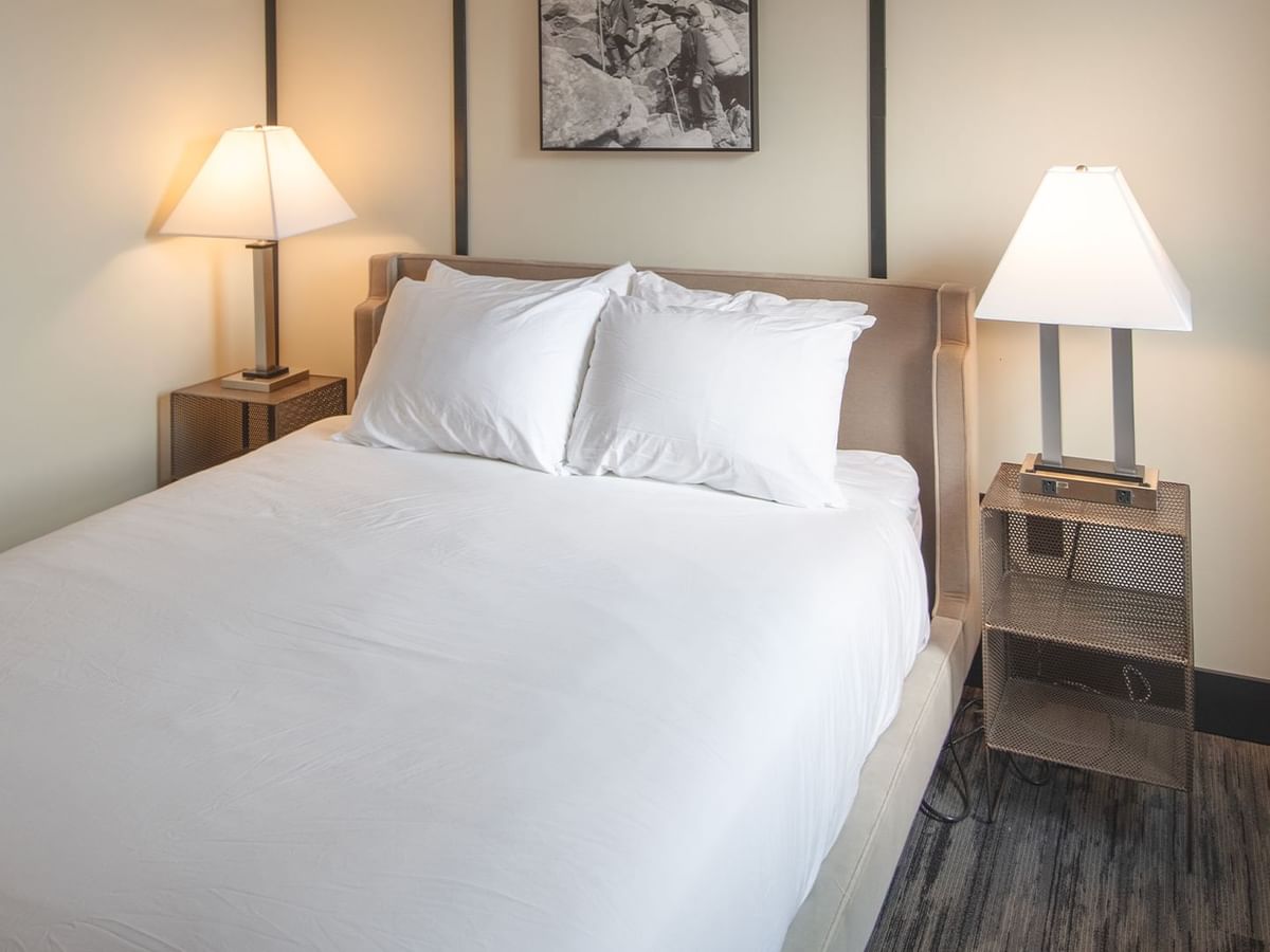 Hotel room with queen bed, night stand, and lamp