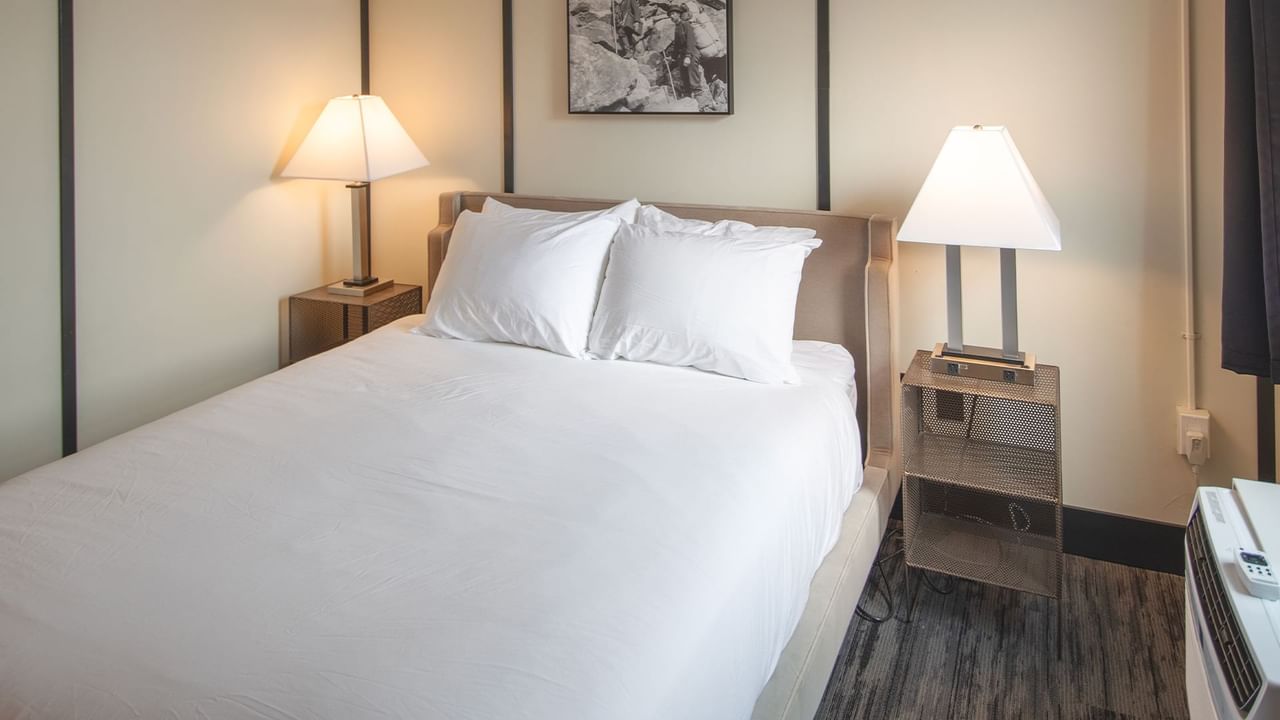 Hotel room with queen bed, night stand, and lamp