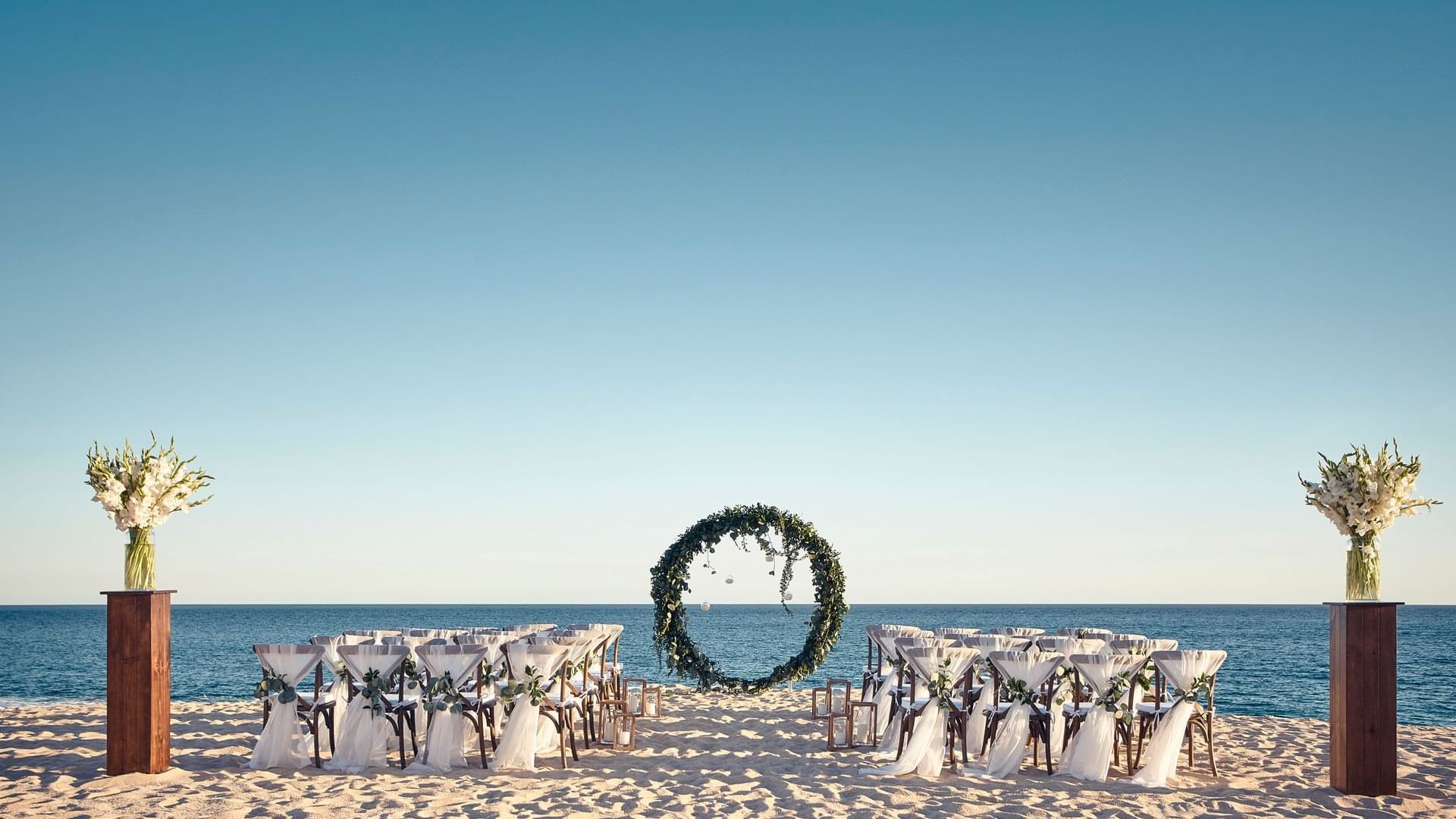 A breathtaking beach ceremony setup with a circular floral arch and an ocean view at Hacienda del Mar Los Cabos