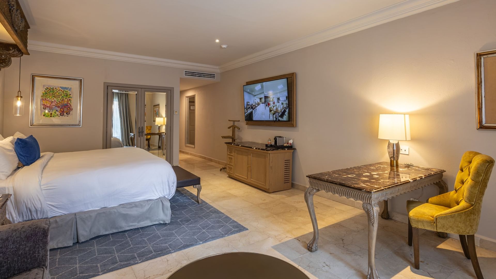 Suite Gran Clase Plus King con cama king, escritorio, sillón amarillo y TV en Quinta Real Monterrey, San Pedro Garza García