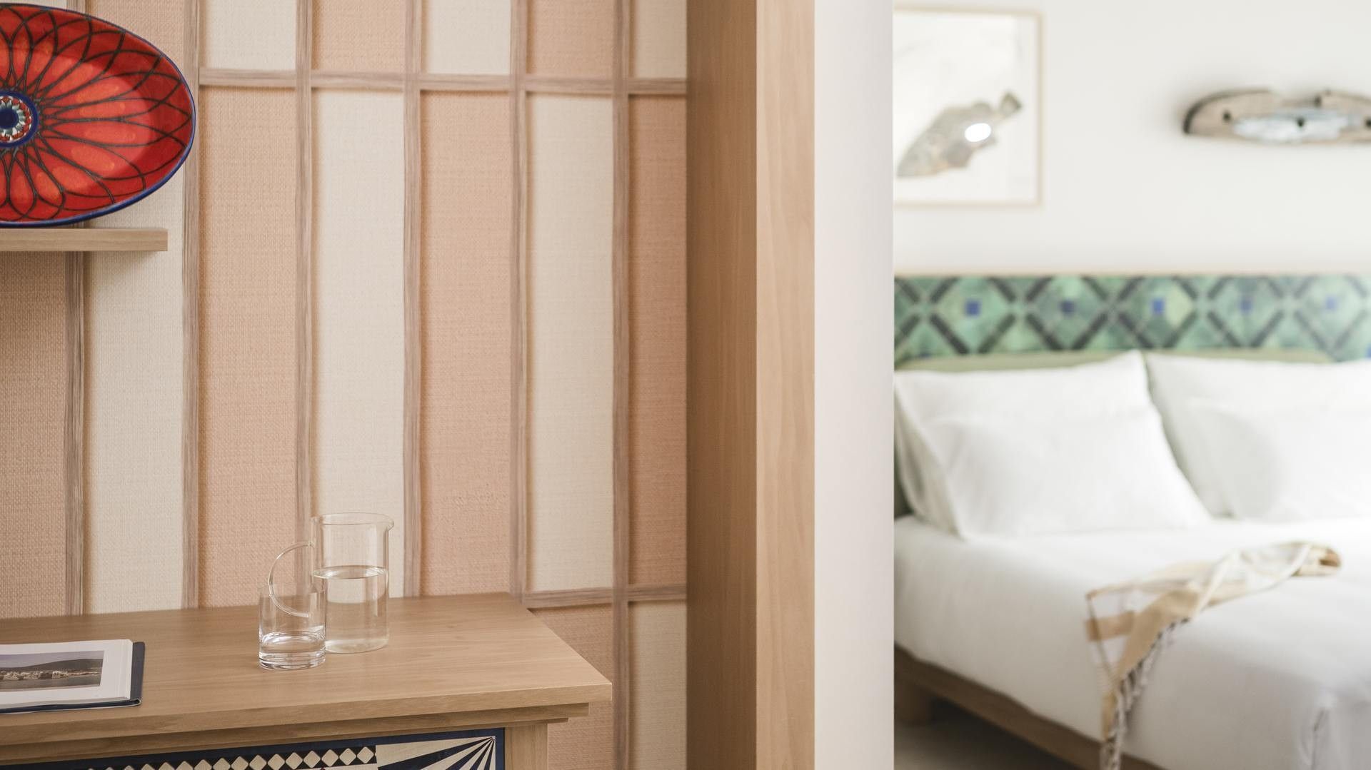 Camera da letto con letti bianchi, bicchieri d'acqua e decorazioni artistiche sulle pareti.