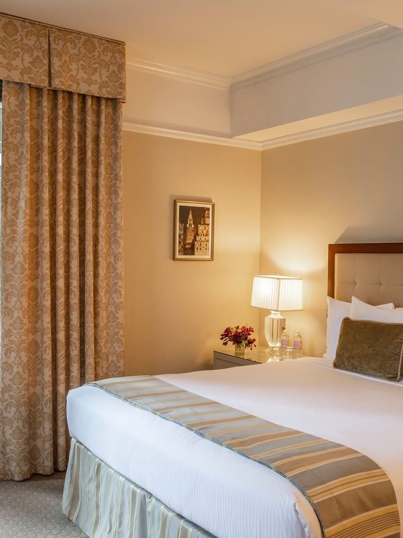 Comfortable queen bed with bedside lamp and large window in Premier City View with Terrace at Warwick New York