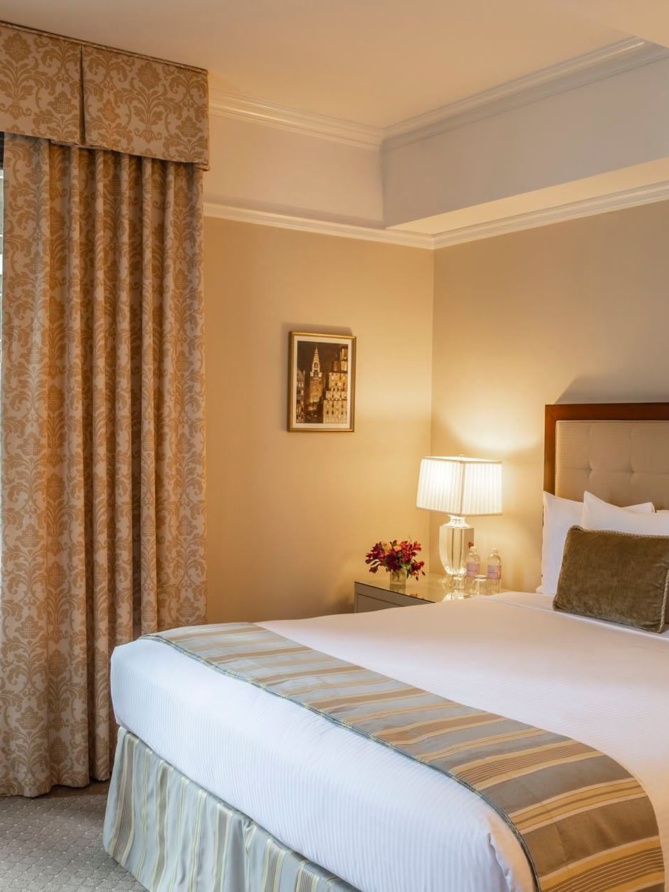 Comfortable queen bed with bedside lamp and large window in Premier City View with Terrace at Warwick New York