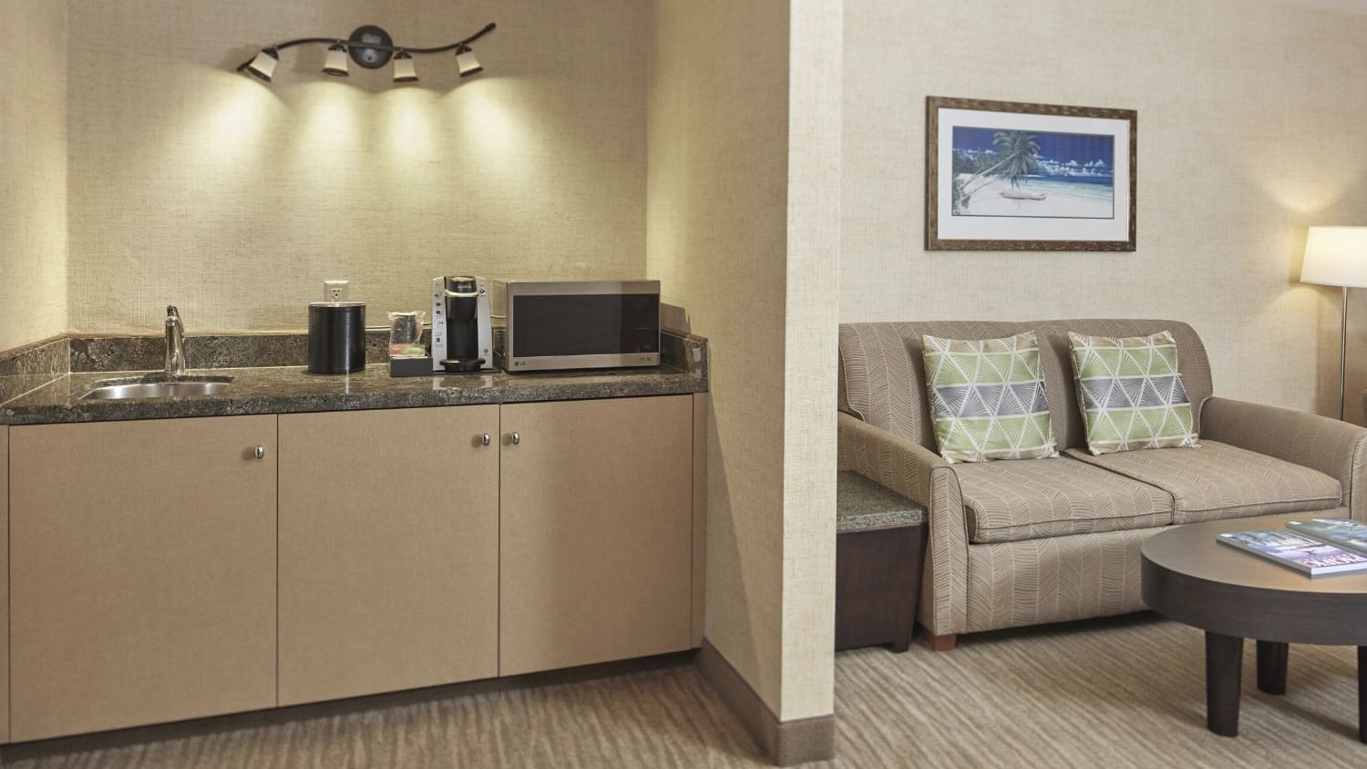 A wide view of a hotel suite's living area and kitchenette.