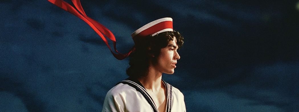 Man in sailor uniform and red hat with ribbon in the wind for Conan Gray's Wishbone World Tour 2026 event.