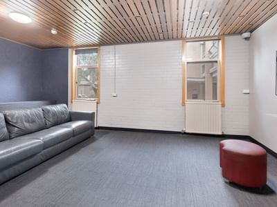 Lounge area with gray leather couch and red ottoman at La Trobe University - Glenn College.