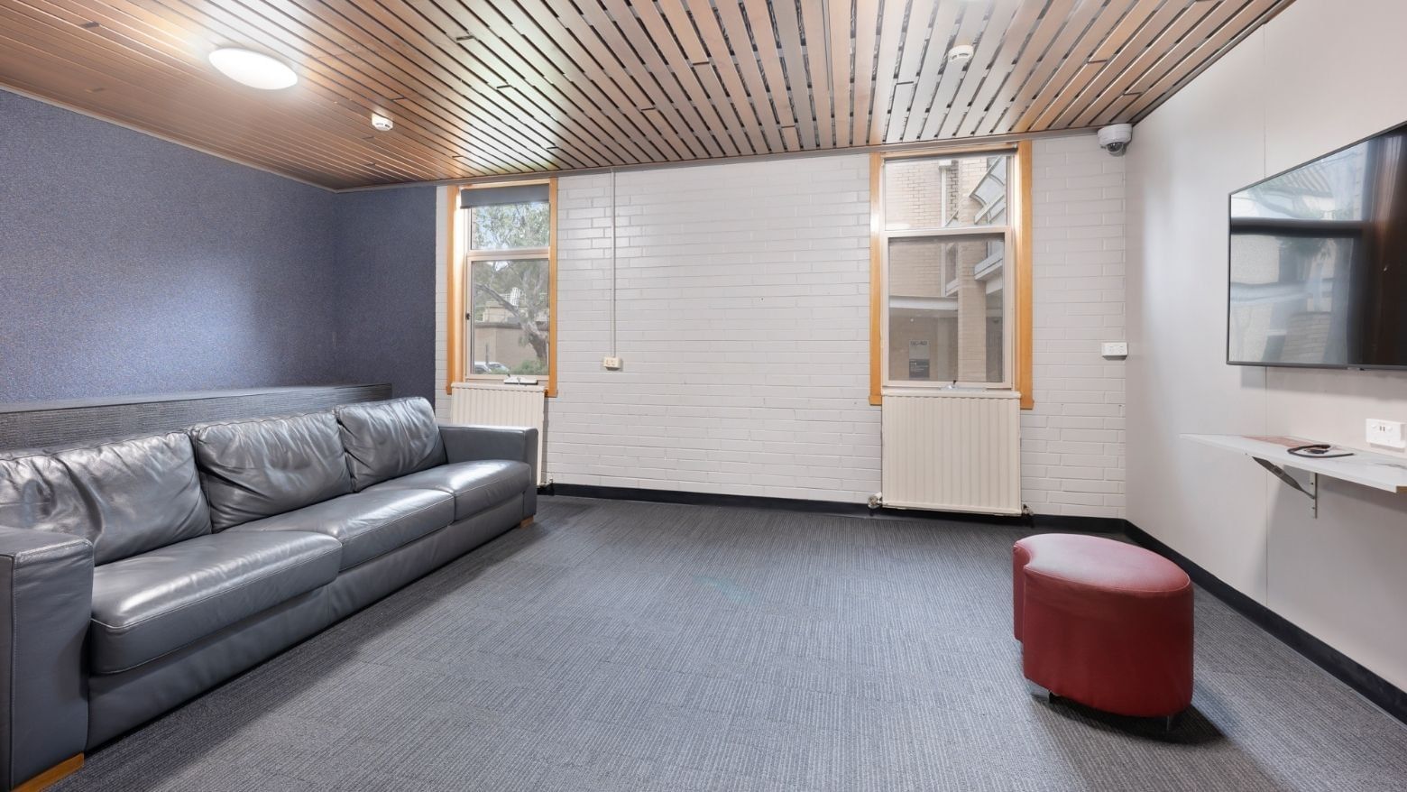 Lounge area with gray leather couch and red ottoman at La Trobe University - Glenn College.