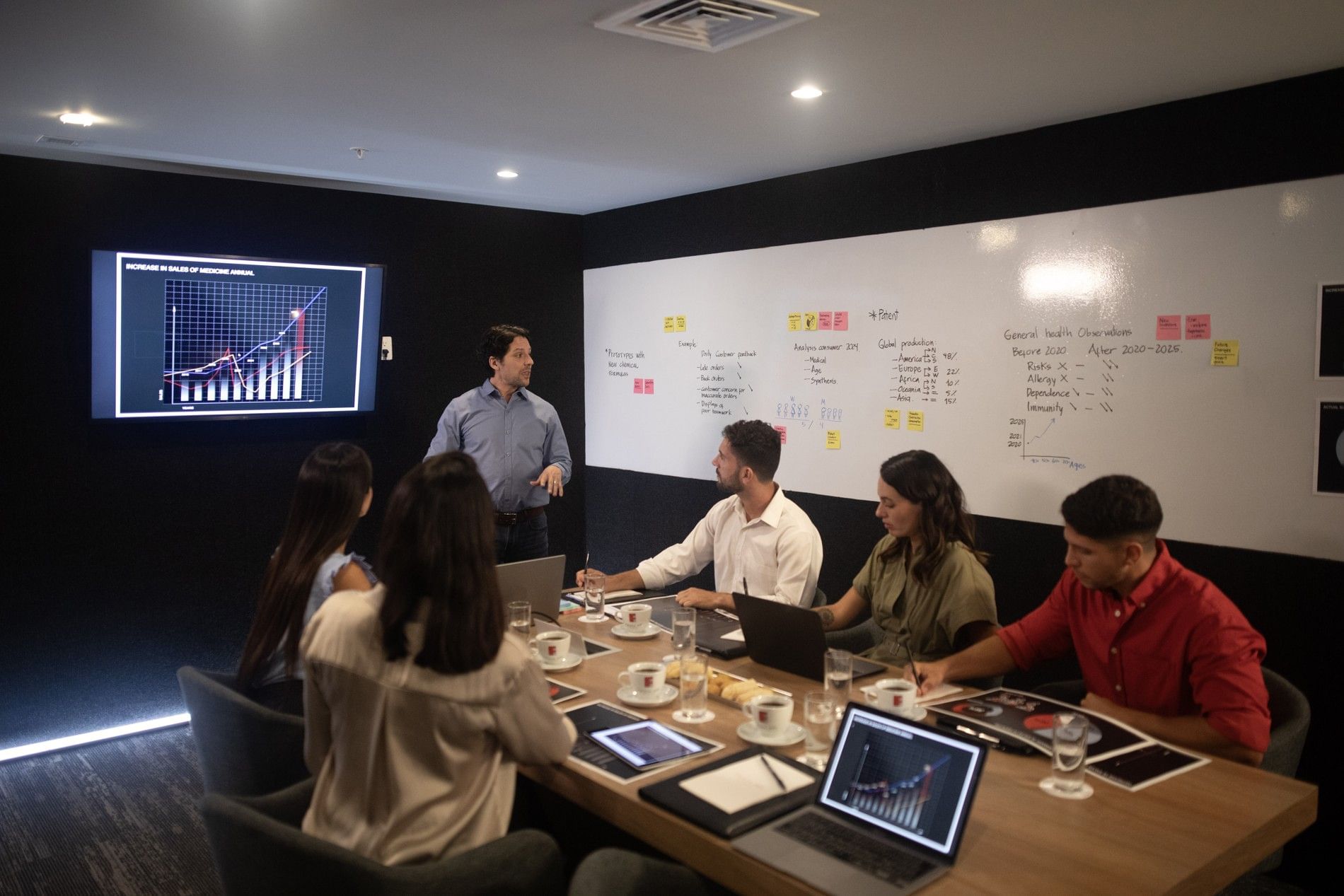 Equipo profesional reunido alrededor de mesa larga en sala de juntas elegante con paredes oscuras en Fiesta Inn