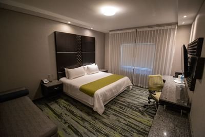 Large bed by a desk under a TV near window in Superior Room at Hotel Mirra, a hotel near US border crossing San Luis, Sonora