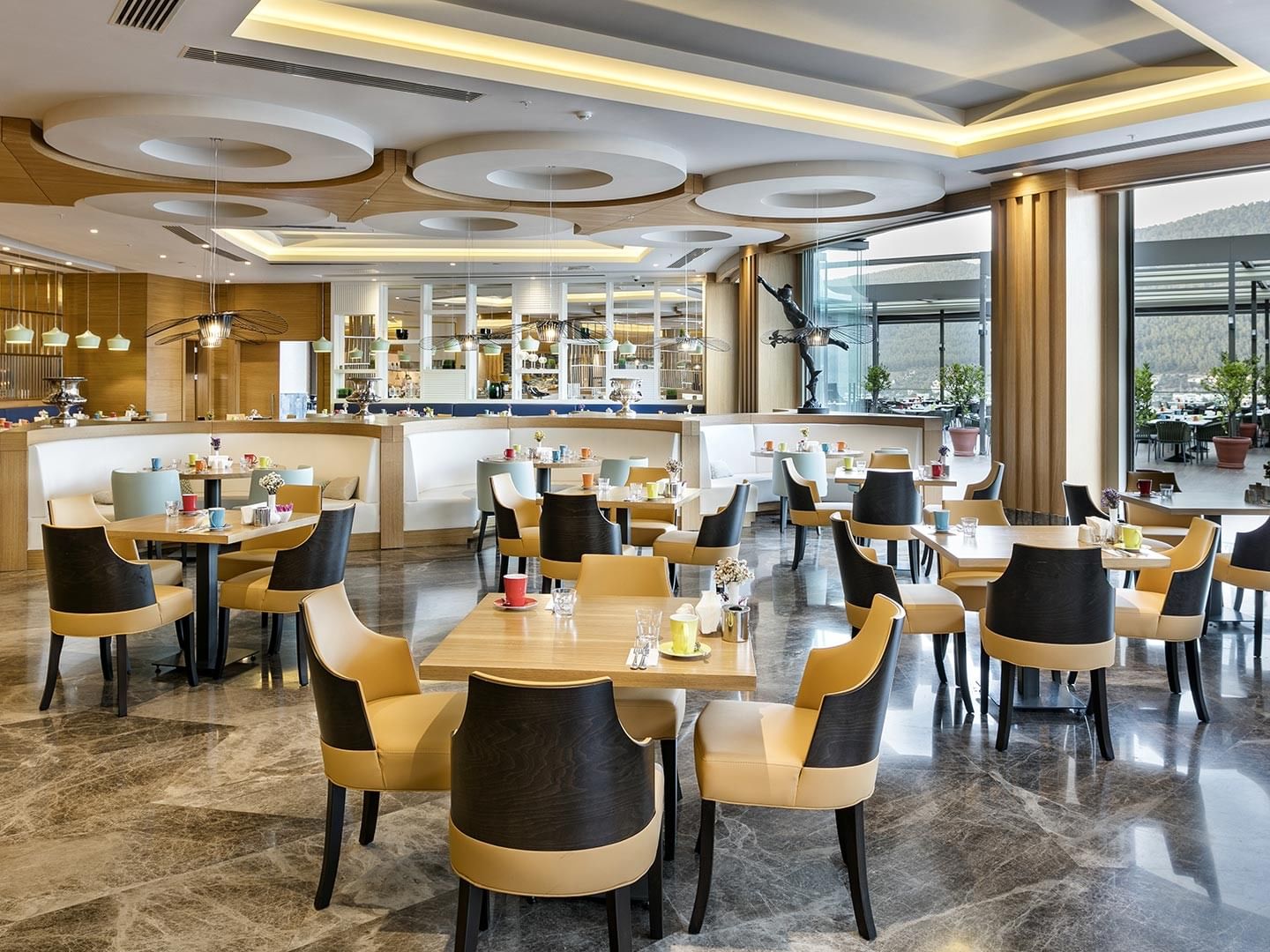 Luxury restaurant interior with glass walls and mountain views at Titanic Luxury Collection Bodrum.