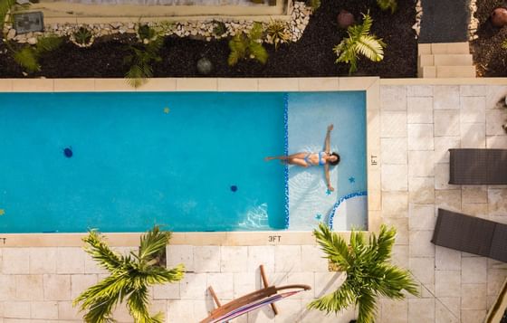View of a woman lounging in the pool at True Blue Bay Hotel