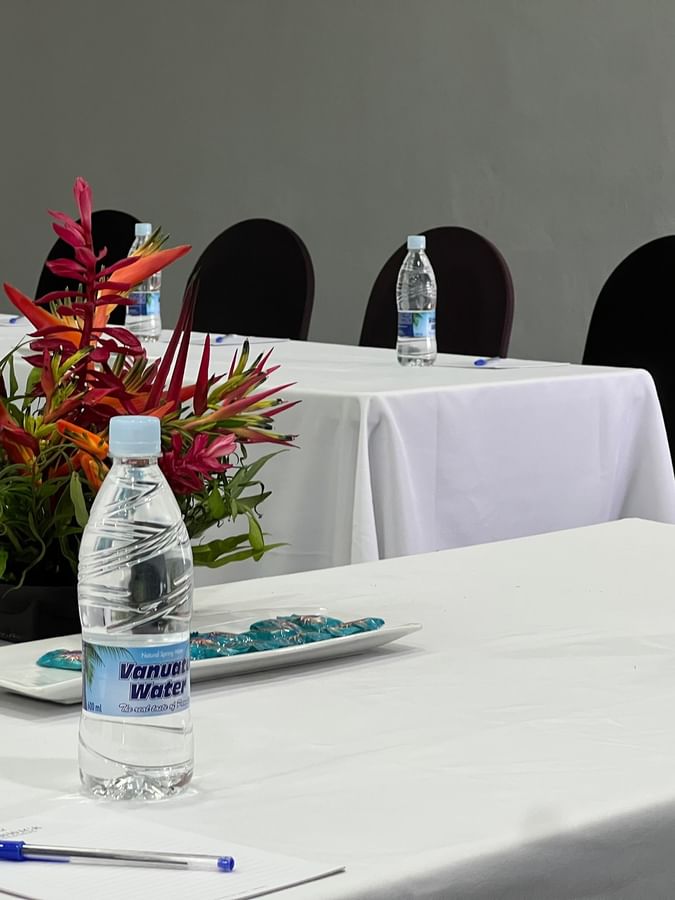 Vanuatu Water bottles by pens and red flowers in Marquee Meeting Room Warwick Le Lagon Port villa