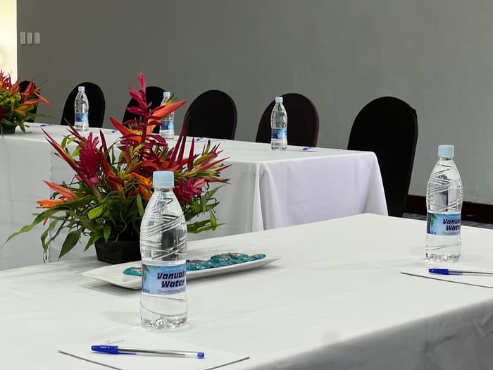 Vanuatu Water bottles by pens and red flowers in Marquee Meeting Room Warwick Le Lagon Port villa