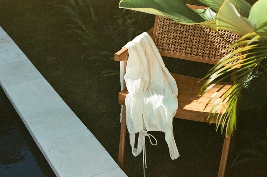 White robe draped over a wooden chair by a pool, surrounded by lawn at Hotel Brookmere