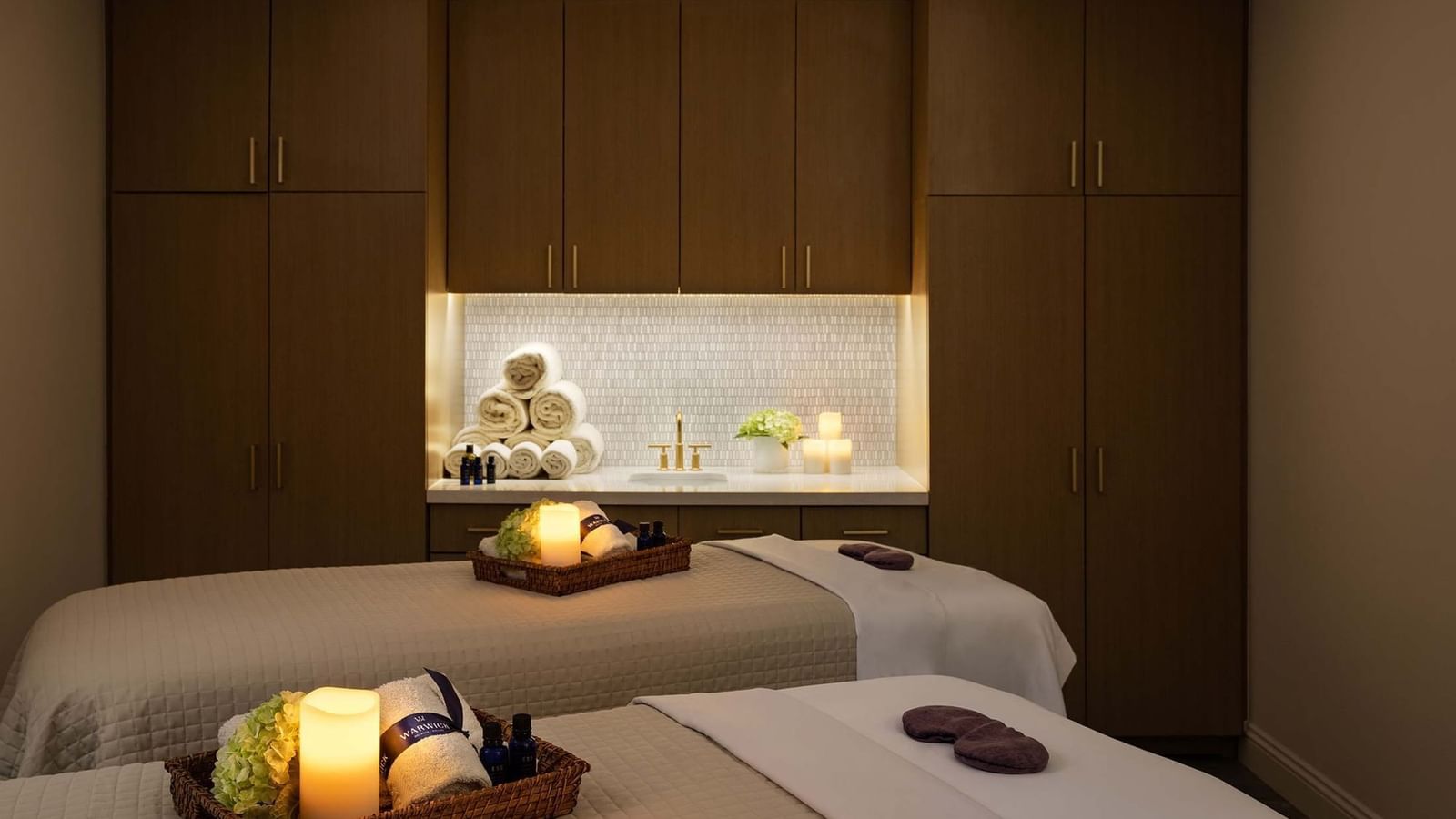 Massage tables with rolled towels under warm light in the serene spa at Warwick Melrose Dallas