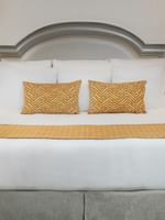 Queen bed with yellow accent pillows by two lamps in Deluxe King at Warwick Melrose Dallas
