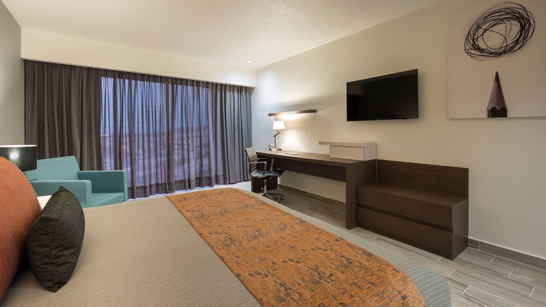 Work desk and wall-mounted TV facing the cozy bed in the King Deluxe Room at Real Inn San Luis Potosi