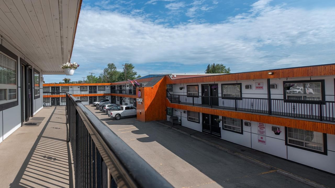 Exterior walkway overlooking Coast Dawson Creek Hotel courtyard with guest room balconies and parking.