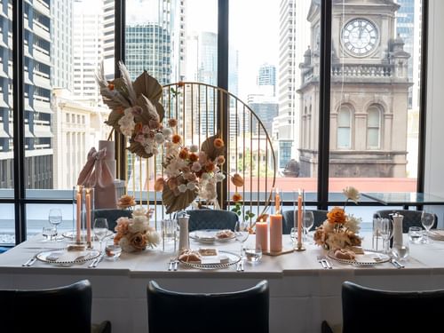 Wedding Dining table with floral centerpiece, overlooking city skyline through large windows at Sofitel Brisbane Central