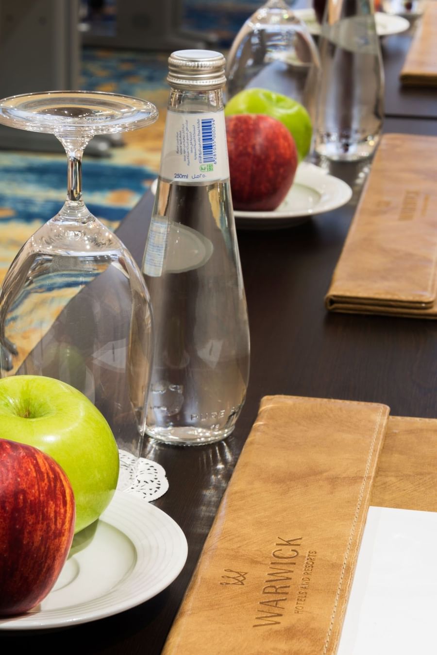 Close-up table featuring a glass of water near apples & an inverted glass in Khalej Meeting Room at Naviti by Warwick Dammam