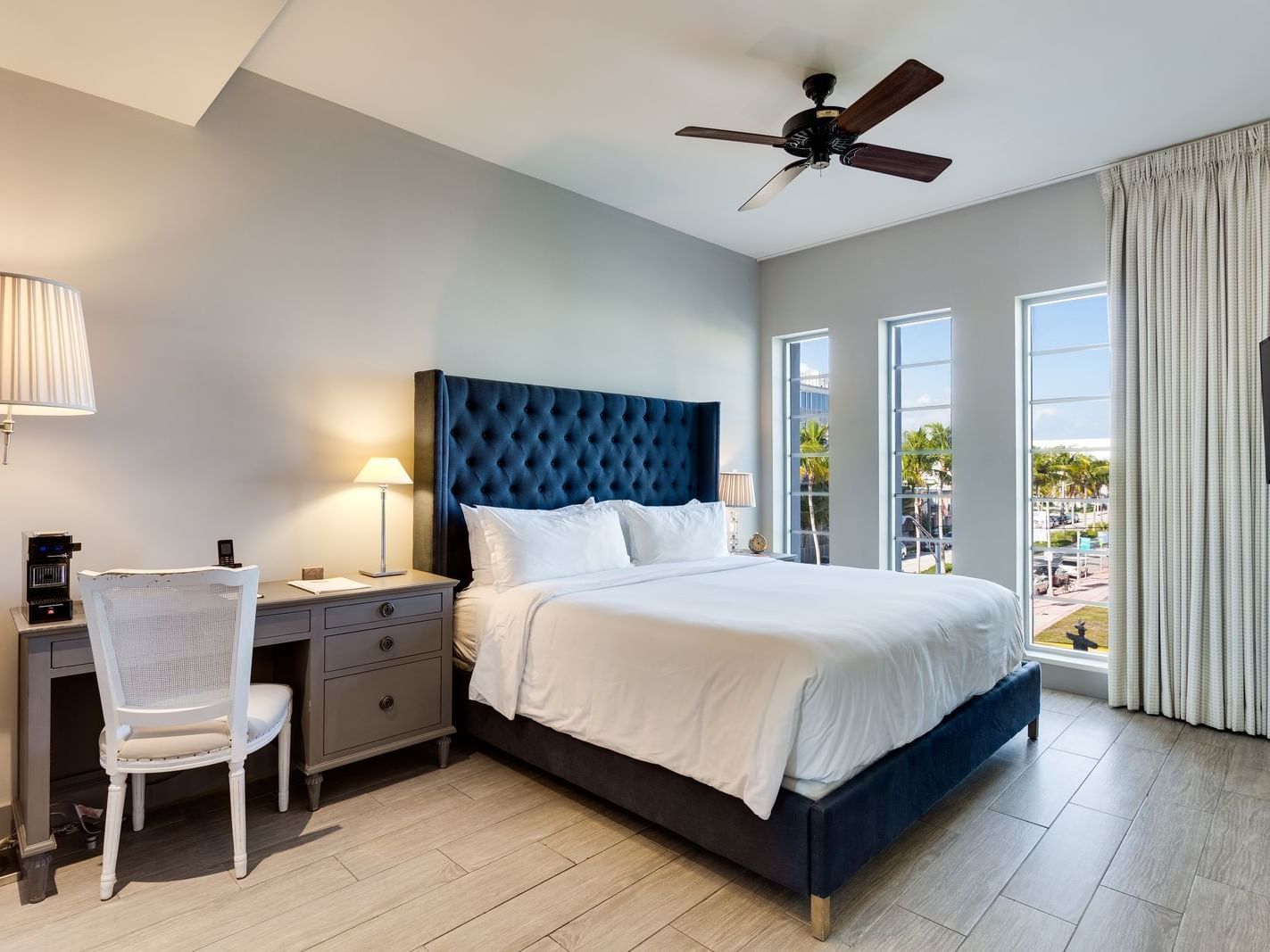 room with large bed and blue headboard with tall windows