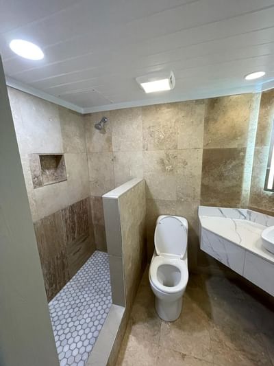 Walk-in tiled shower next to a white toilet and marble vanity counter in the bathroom at Emerald Beach Resort