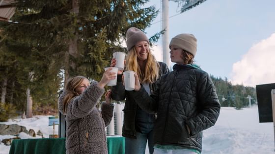 Happy family toasting outdoors with beverage cups at Blackcomb Springs Suites